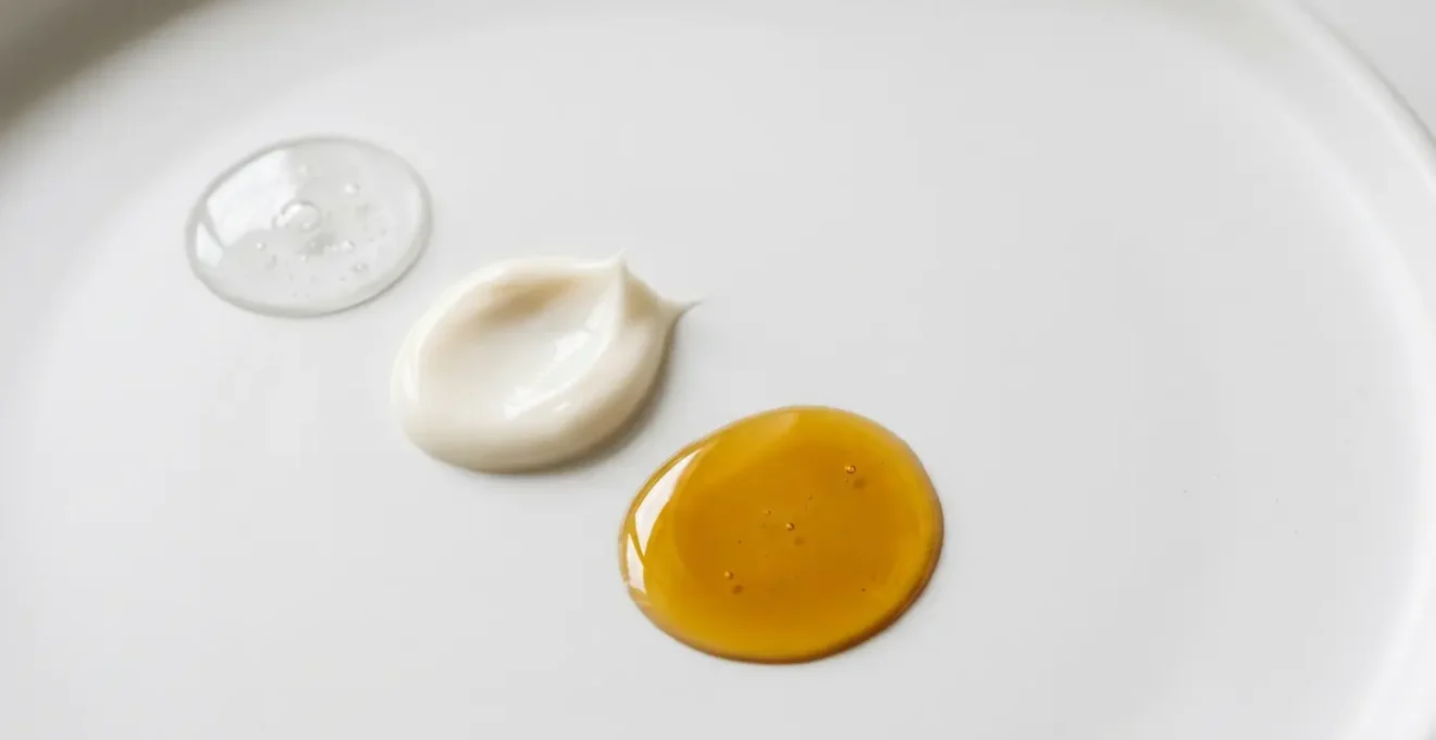 Composizione minimalista di prodotti skincare stratificati con texture diverse su superficie pulita