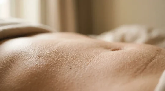 Dettaglio macro di superficie cutanea con texture naturale e luce morbida che evidenzia la cura del corpo